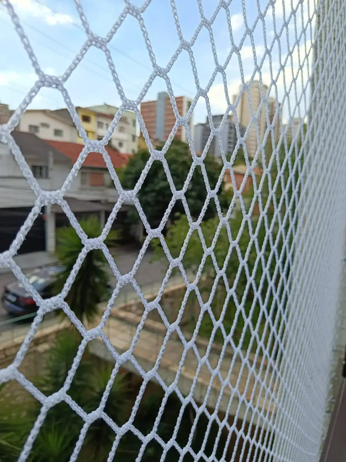 Instalação de rede de proteção malha 3x3 em janela residencial em São Paulo, garantindo segurança para gatos e crianças.