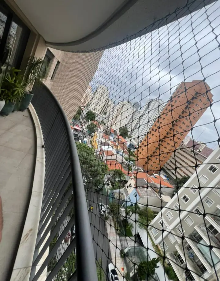 Instalação de rede de proteção preta em sacada de apartamento em São Paulo, oferecendo segurança e discrição.