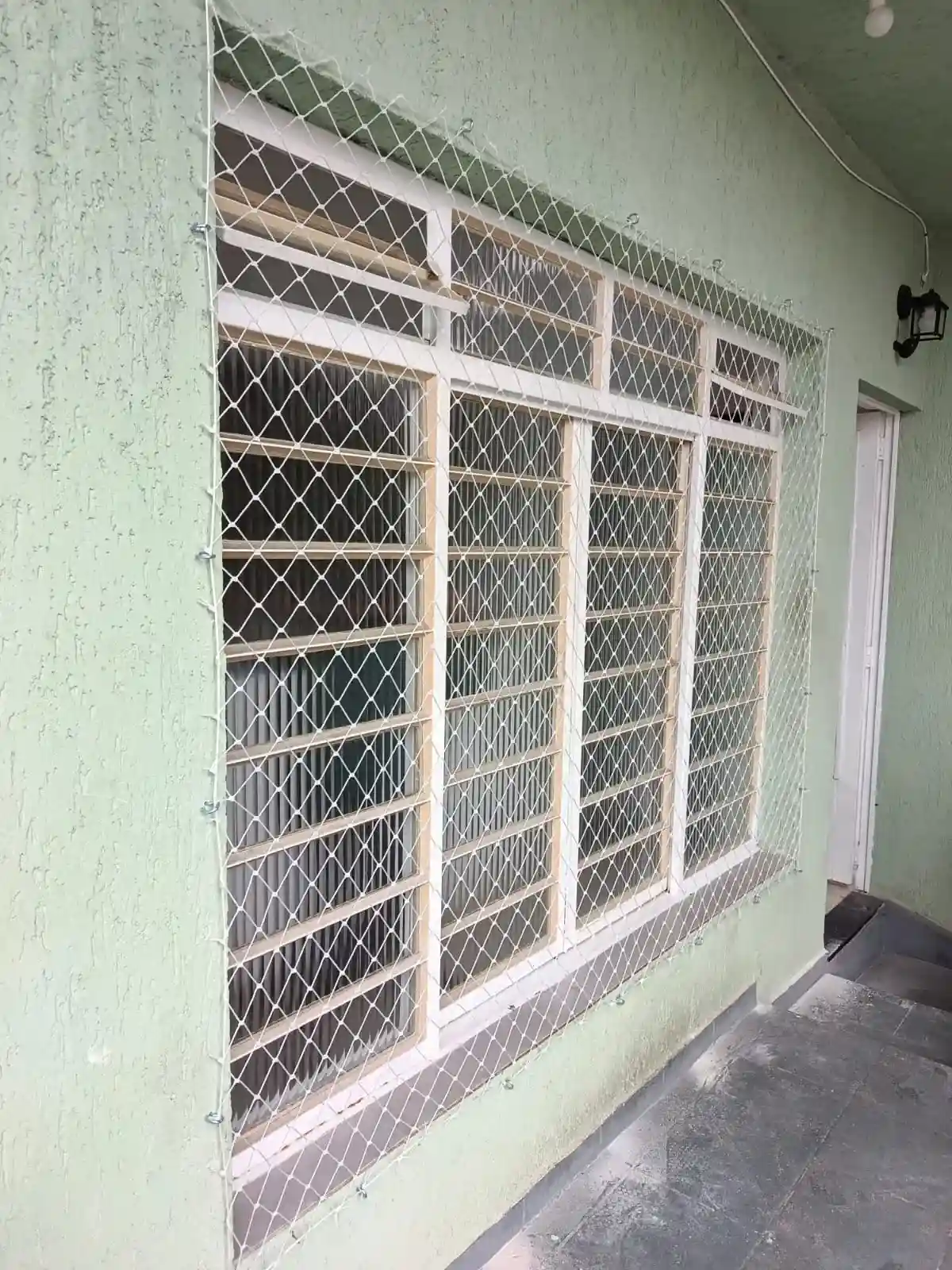Profissional instalando tela de proteção em uma janela residencial